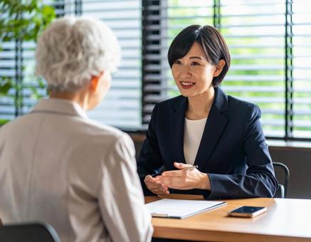 顧客と話をするスーツ姿の女性 顧客と話をするスーツ姿の女性の写真