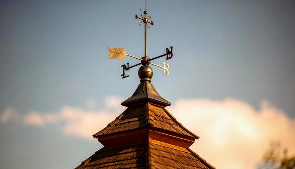 青空と風見鶏が立つ屋根の写真
