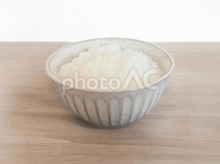 木のテーブルに置いたお粥を盛った茶碗 お粥,風邪,優しいの写真素材