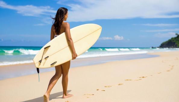 サーフボードを持って砂浜を歩く女性 サーフボードを持って砂浜を歩く女性の写真