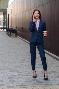 街なかでコーヒー片手に電話するビジネスウーマン ビジネスウーマン,ビジネス,女性の写真素材