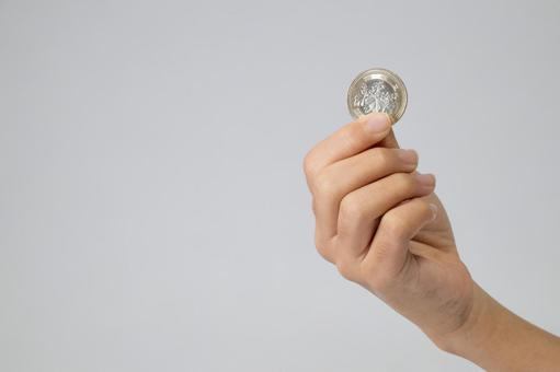 白背景で500円玉を軽く持つ子供の手 500円玉,お金,500円の写真素材