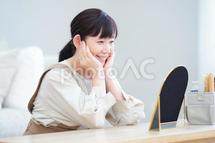 鏡を見ながら微笑む中年女性の美容タイム 主婦,中年,シニアの写真素材