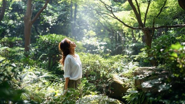 森の中で光を浴びる女性 森の中で光を浴びる女性の写真