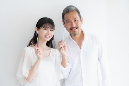 白バックで歯磨きをするミドルの夫婦 白バックで歯磨きをするミドルの夫婦 歯磨き,家族,ホワイトニングの写真素材