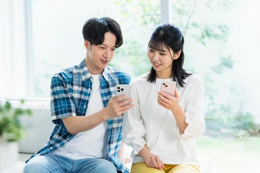 リビングでスマホを見るカップル スマホ,笑顔,カップルの写真素材