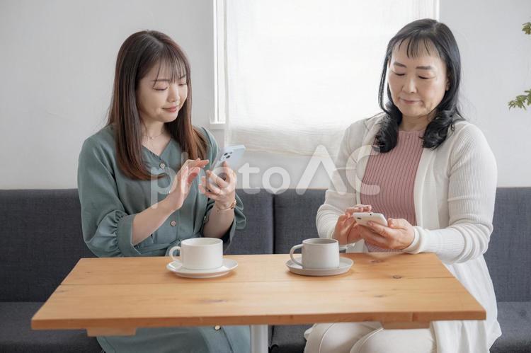 カフェでスマホをいじる二人の女性 スマートフォン,カフェ,テーブルの写真素材