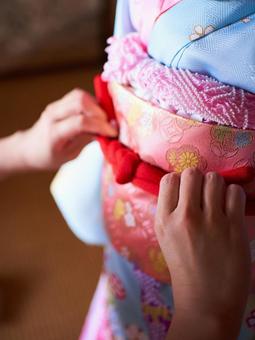 七五三の女の子の帯締めを結ぶ手のアップ 七五三,帯締め,結ぶの写真素材