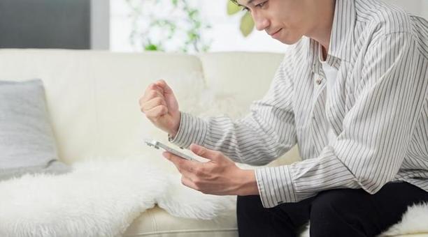 スマホを見てガッツポーズをする男性 ガッツポーズ,男性,スマホの写真素材