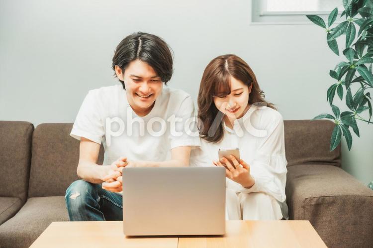 ノートパソコンとスマホを使う男女 ノートパソコン,スマホ,検索の写真素材