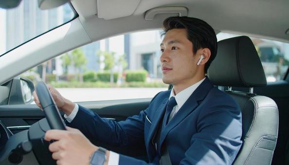 ワイヤレスイヤホンをつけて運転する男性 ワイヤレスイヤホンをつけて運転する男性の写真