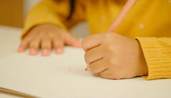 お絵かきをする子供の手もと お絵かきをする子供の手もとの写真