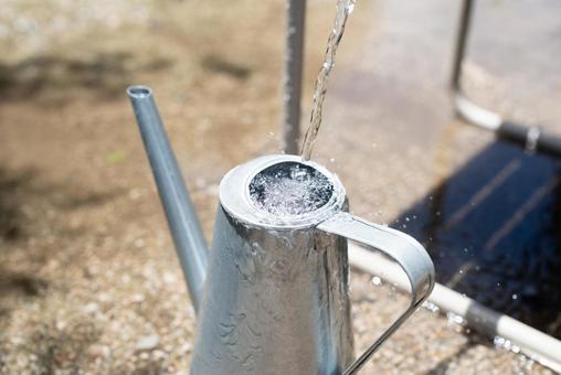 A tin watering can pouring water, JPG