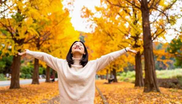 紅葉の中で深呼吸する秋服の日本人女性 紅葉の中で深呼吸する秋服の日本人女性の写真