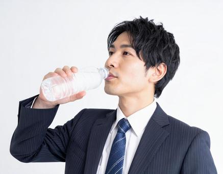 ペットボトルの水を飲むビジネスマン ペットボトルの水を飲むビジネスマンの写真