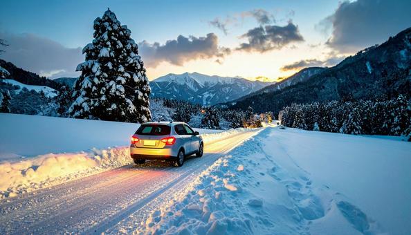 大雪が降った翌日の雪が積もった道を走る車の写真