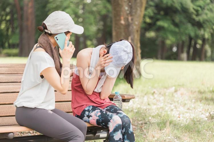 運動中に頭痛で苦しむ女性と救急車を呼ぶ人 頭痛,運動,救急車の写真素材
