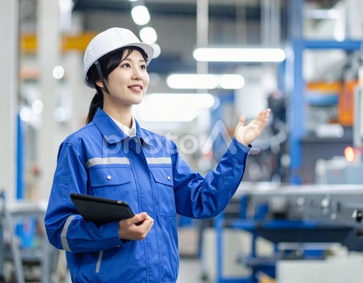 工場で案内する女性作業員の笑顔とプロ意識 工場,女性,作業員の写真素材