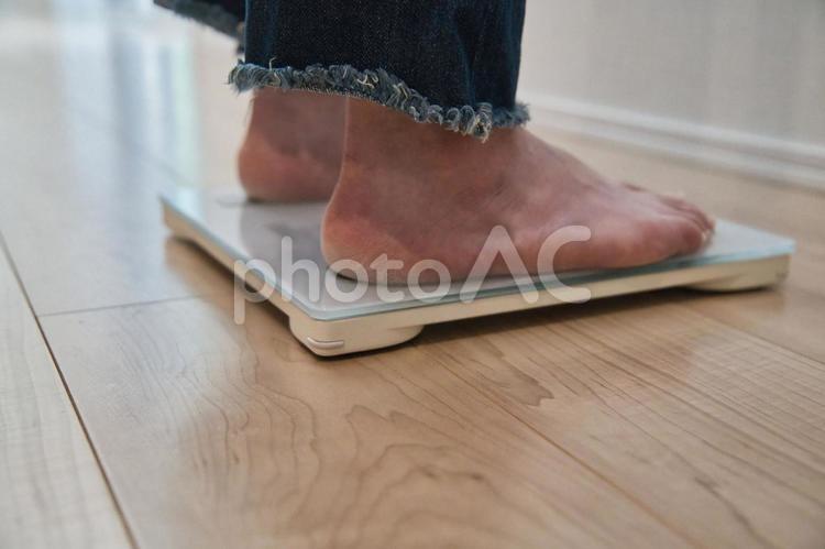 リビングで体重計にそっと足を乗せる女性 体重計,体重管理,健康維持の写真素材