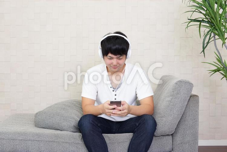 くつろぐ男性 スマホ,スマートフォン,ヘッドフォンの写真素材