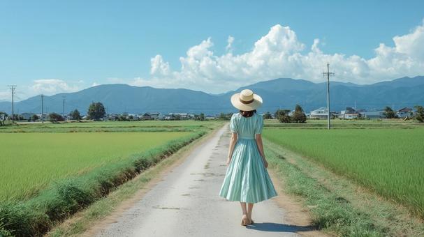 田園風景の道を歩くワンピース姿の女性 田園風景の道を歩くワンピース姿の女性の写真