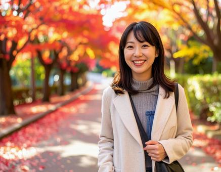 紅葉の道を散歩する女性の写真