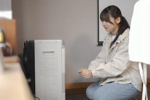 電気機器の前に居る女性 暖房,ストーブ,寒いの写真素材