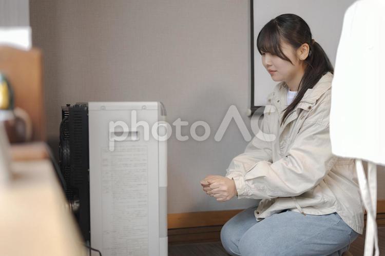 電気機器の前に居る女性 暖房,ストーブ,寒いの写真素材