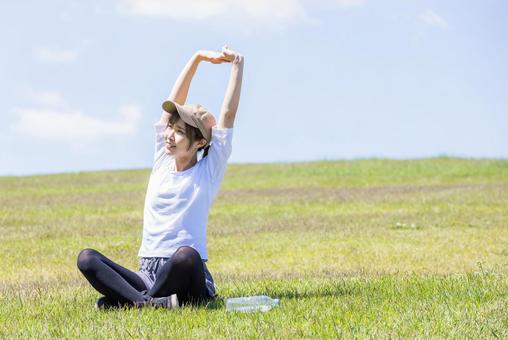 緑の丘でストレッチする女性 緑の丘でストレッチする女性 女性,丘,ストレッチの写真素材