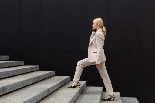 オフィスビルの外の階段を登りながら電話しているビジネスウーマン ビジネスウーマン,ビジネス,女性の写真素材