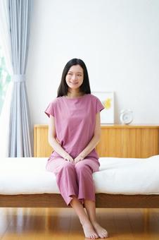 ベッドに座り横を見るロングヘアの女性 女性,ベッド,座るの写真素材