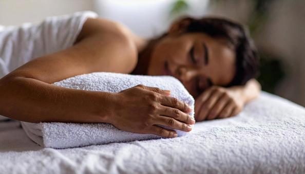 片腕の下にバスタオルを置いて眠る女性患者 片腕の下にバスタオルを置いて眠る女性患者の写真