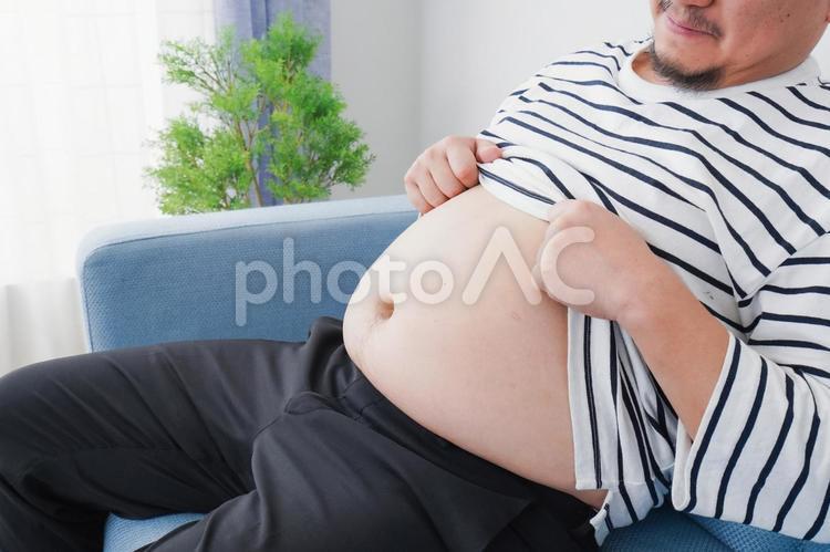 食べ過ぎで肥満体型の男性 ソファ,中国人,白背景の写真素材
