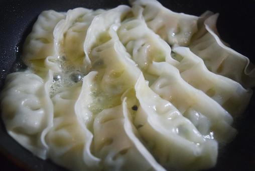 焼いている餃子 焼いている餃子の写真