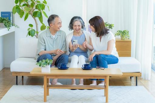 リビングでスマホを見るシニア夫婦と子供 シニア,夫婦,スマホの写真素材