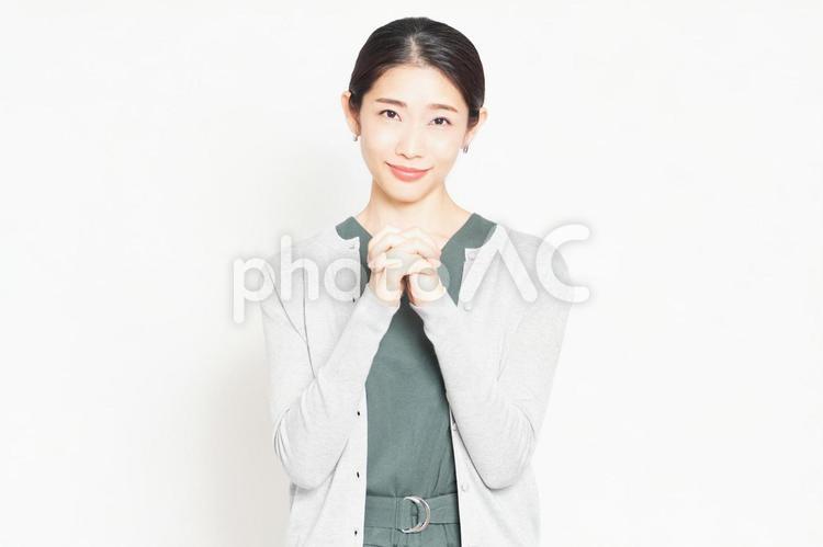 白背景の前で、お願いのポーズをする女性 主婦,お願い,女性の写真素材