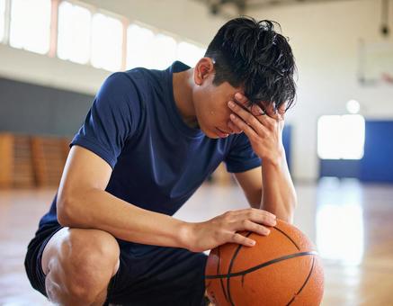 体育館で悔し涙を流すバスケットボール選手 体育館で悔し涙を流すバスケットボール選手の写真