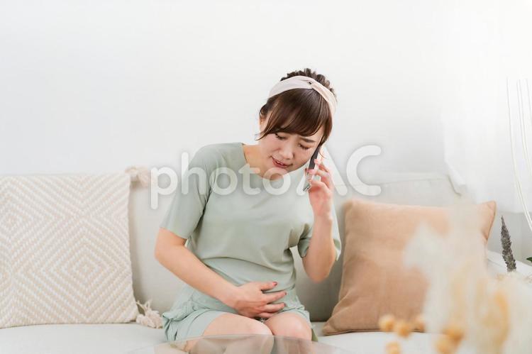 陣痛がきて電話するアジア人女性（妊婦） 陣痛,流産,破水の写真素材