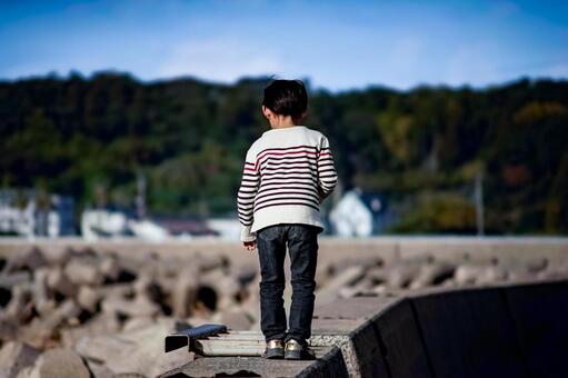 ＜素材＞秋の防波堤を歩く迷子の男の子 子供,迷子,海の写真素材