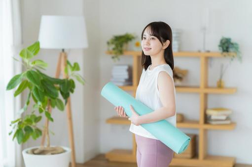 リビングでヨガをする若い女性 リビングでヨガをする若い女性 トレーニング,ヨガマット,持つの写真素材