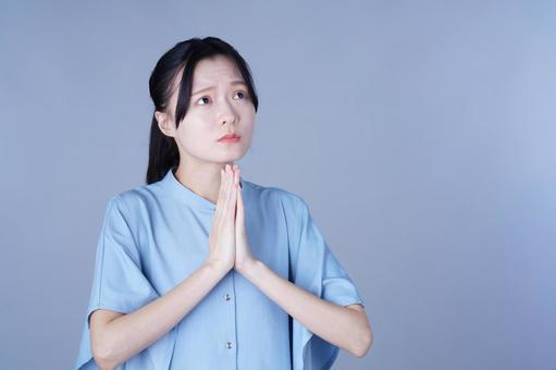 お願いポーズをする青い服の女性 女性,お願い,合掌の写真素材