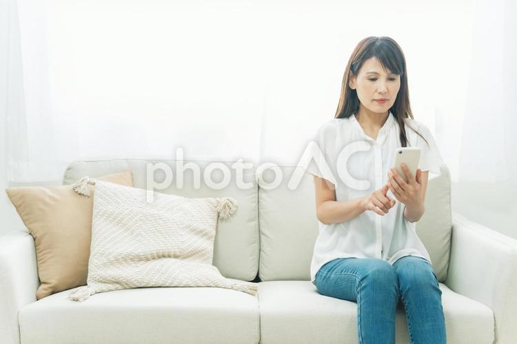 ソファに座るミドル世代の女性（困る） スマホ,アプリ,スマートフォンの写真素材