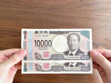 机上で2万円を持つ女性の手元 机上で2万円を持つ女性の手元 お金,給付金,手の写真素材