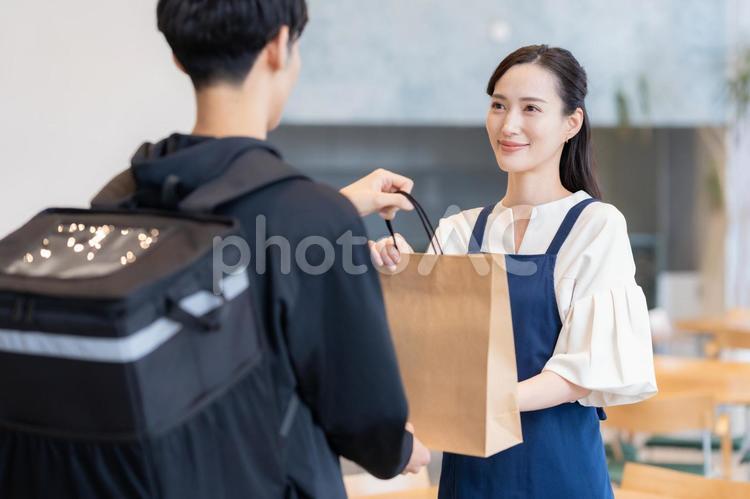 デリバリーを配達員に頼むカフェの店員 カフェ,テイクアウト,デリバリーの写真素材