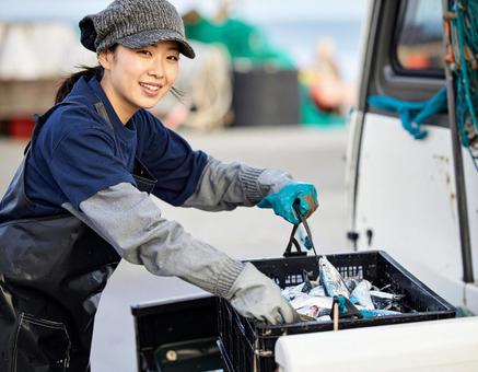 水揚げした魚介類を軽トラに積む漁師の女性 水揚げした魚介類を軽トラに積む漁師の女性の写真