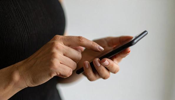 スマートフォンを操作する女性の手元 スマートフォンを操作する女性の手元の写真