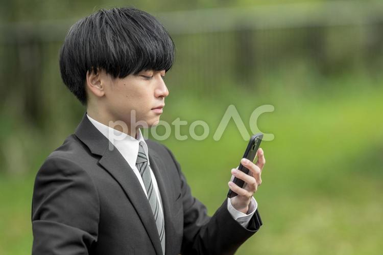 屋外でスマホを使うビジネスマン 就職,キャリア,若いの写真素材