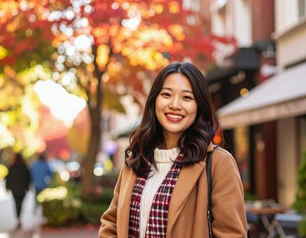 秋の街を歩く笑顔の女性の写真