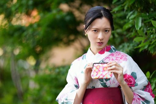 浴衣姿の女性が財布を持って見つめる 女性,財布,がま口の写真素材
