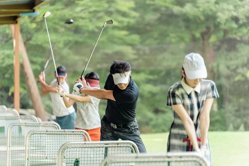 ゴルフ練習場でスイングの練習する男女 ゴルフ練習場でスイングの練習する男女 ゴルフ,ゴルフ練習場,打ちっぱなしの写真素材